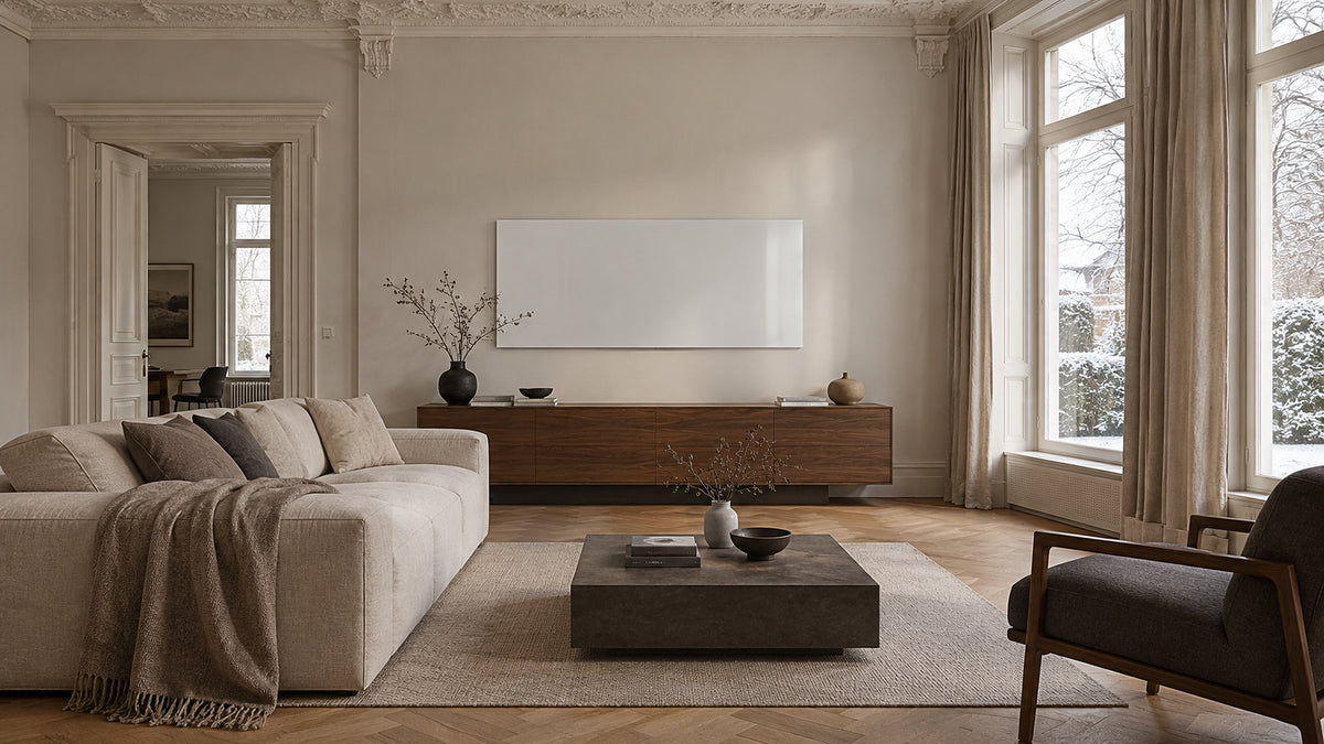 Weiße Glas-Infrarotheizung über einem Sideboard in einem hellen Altbau-Wohnzimmer mit Stuck und Fischgrätparkett